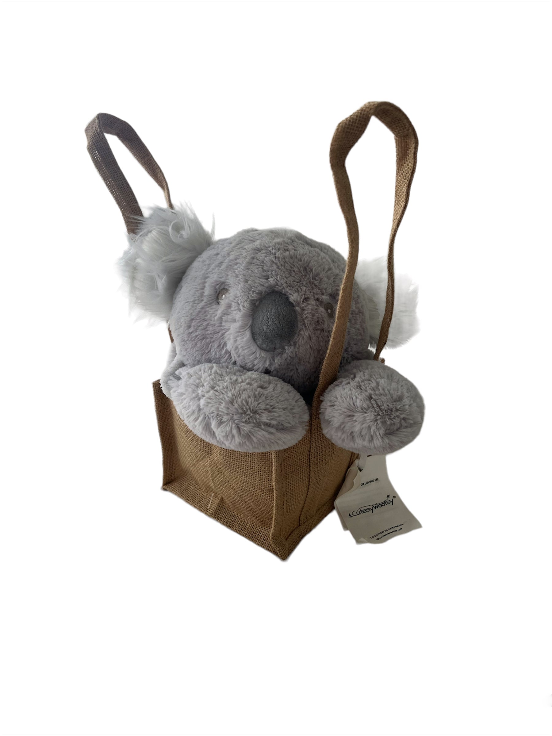 Peaceful, adorable stormy-grey cloud coloured, plush Koala head with white fluffy ears sitting resting with its paws, propped up in a natural, brown hessian jute bag