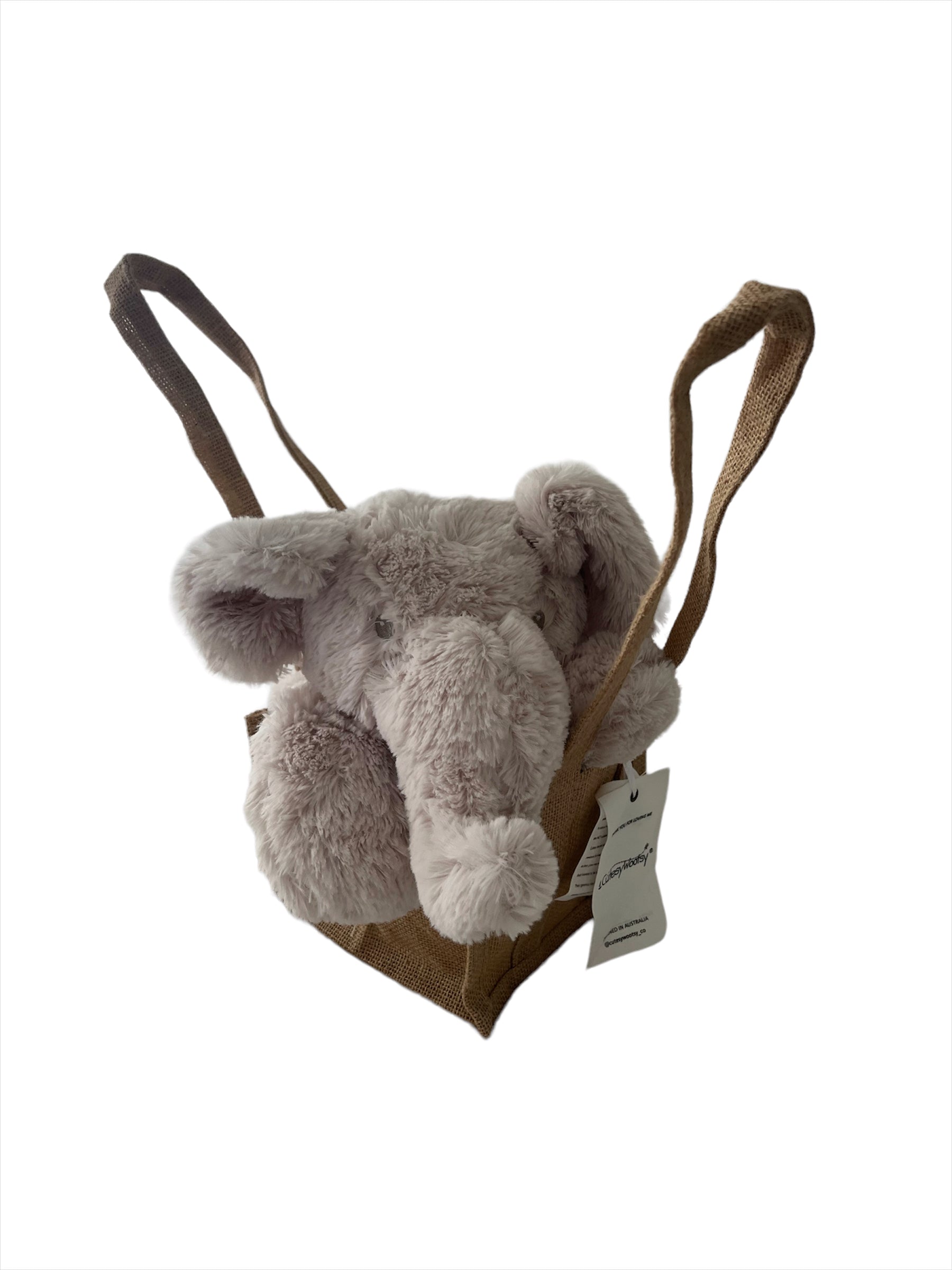 Comfortable-beige coloured, fluffy plush elephant head with a long snuggle nose and floppy ears resting adorably on its paws, sitting propped up in a natural, brown hessian jute bag